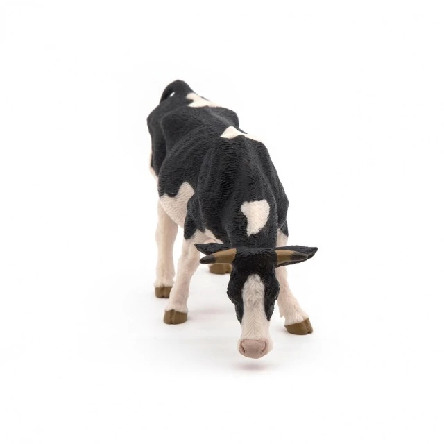 Black and white grazing cow figurine