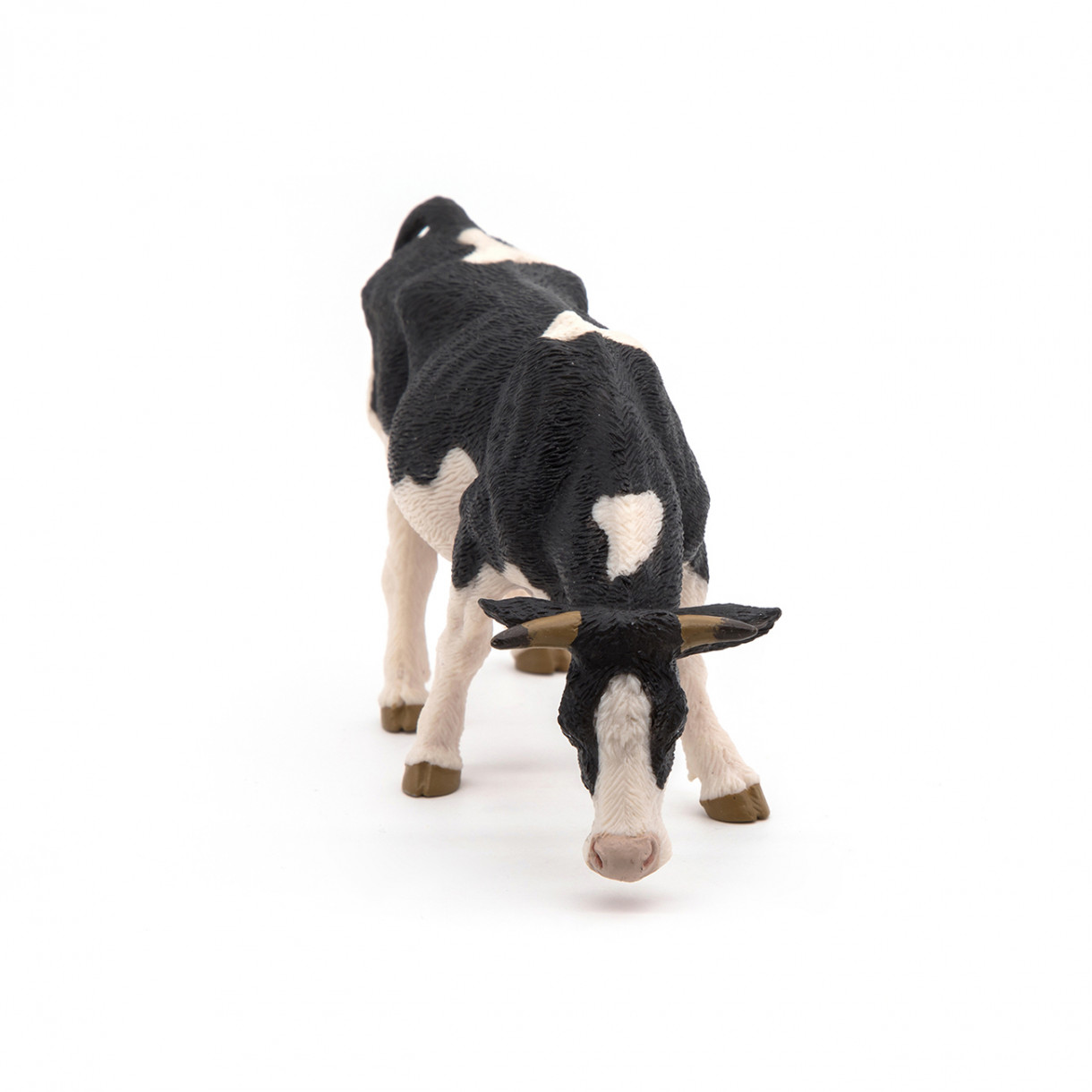 Black and white grazing cow figurine