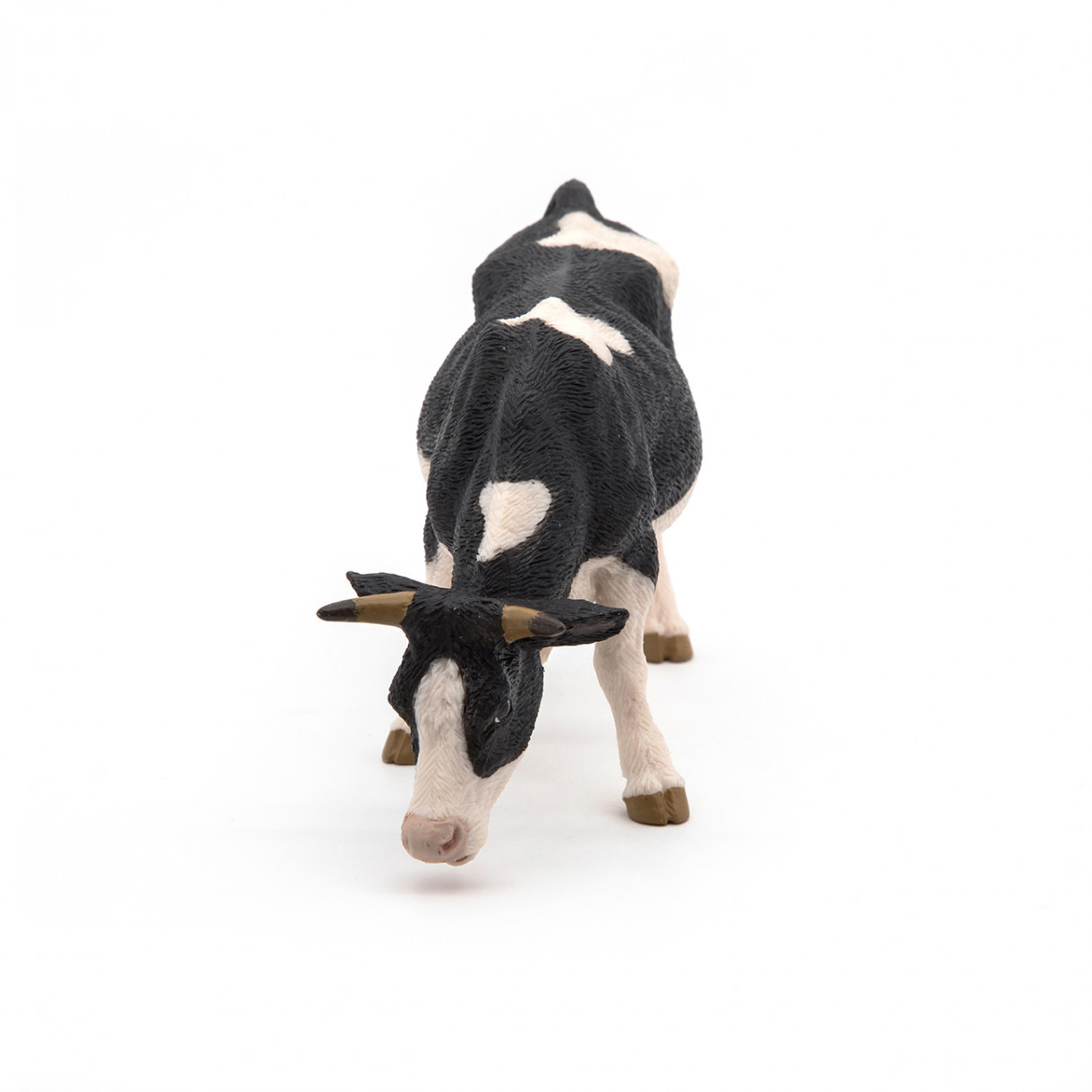 Black and white grazing cow figurine